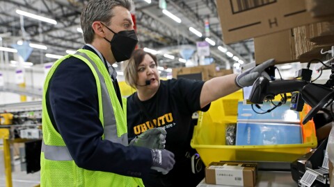 A photo of two employees working with packages at the Hamilton robotics facility.